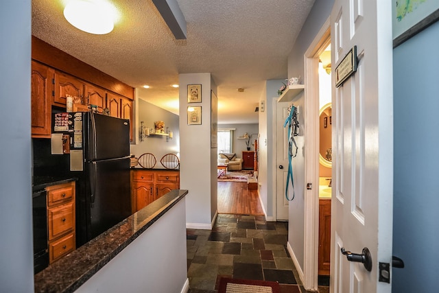 19 Shelburne Rd Unit 19, Merrimack, NH 03054 - kitchen featuring brown cabinets, freestanding refrigerator, a textured ceiling, stone finish flooring, and dark stone countertops