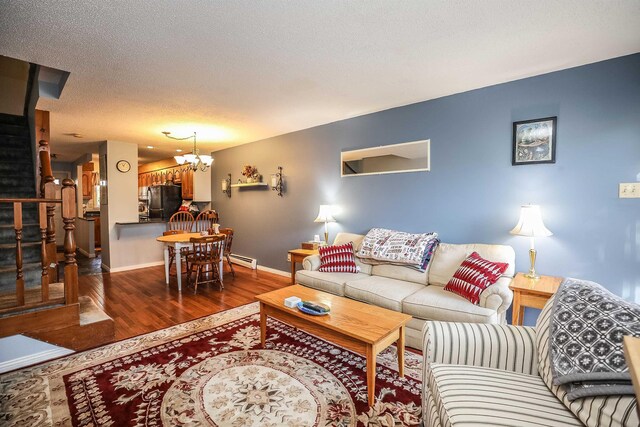 19 Shelburne Rd Unit 19, Merrimack, NH 03054 - living area with a baseboard radiator, wood finished floors, stairs, a textured ceiling, and a chandelier