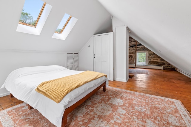 526 River Rd, Lyme, NH 03768 - bedroom with baseboard heating, a skylight, hardwood / wood-style floors, and lofted ceiling