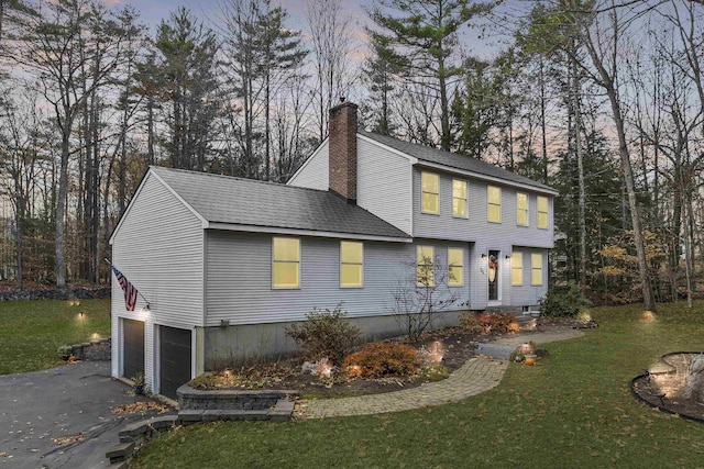 55 Trask Side Rd, Alton, NH 03810 - property exterior at dusk featuring a garage, driveway, a chimney, a yard, and a shingled roof