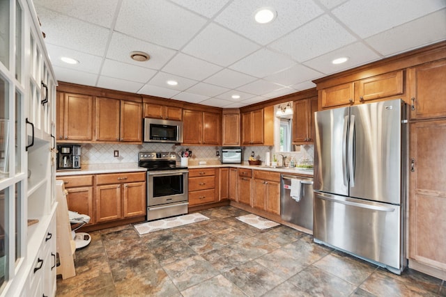183 Summer St, Newport, NH 03773 - kitchen featuring stainless steel appliances, brown cabinets, light countertops, backsplash, and a drop ceiling