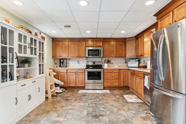 183 Summer St, Newport, NH 03773 - kitchen featuring appliances with stainless steel finishes, brown cabinets, light countertops, decorative backsplash, and a drop ceiling