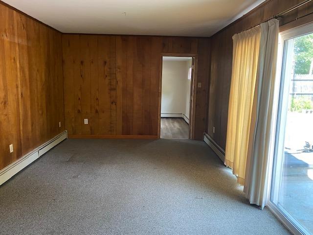 15 Vernon Ave, Rochester, NH 03867 - unfurnished room featuring wood walls, light colored carpet, and a baseboard radiator