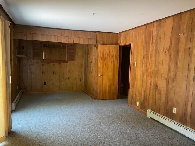 15 Vernon Ave, Rochester, NH 03867 - carpeted empty room featuring a baseboard heating unit and wood walls