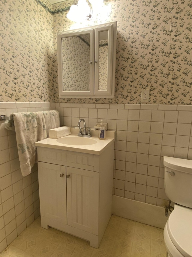15 Vernon Ave, Rochester, NH 03867 - bathroom with wallpapered walls, tile walls, wainscoting, vanity, and tile patterned floors