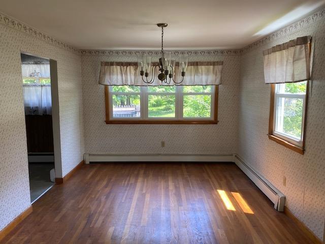 15 Vernon Ave, Rochester, NH 03867 - unfurnished dining area with a baseboard radiator, healthy amount of natural light, wood finished floors, a chandelier, and wallpapered walls