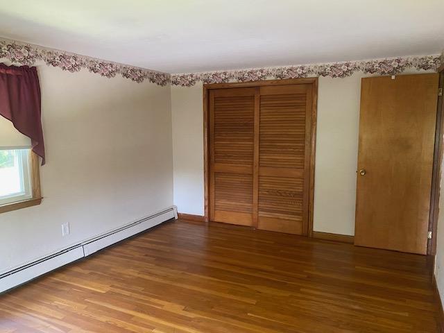 15 Vernon Ave, Rochester, NH 03867 - unfurnished bedroom featuring a baseboard heating unit, wood finished floors, and a closet