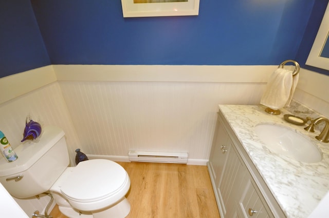17 Village W Dr Unit 11, Bristol, NH 03222 - half bathroom with baseboard heating, vanity, wood finished floors, wainscoting, and a decorative wall