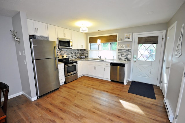 17 Village W Dr Unit 11, Bristol, NH 03222 - kitchen featuring appliances with stainless steel finishes, a baseboard radiator, decorative backsplash, and white cabinetry