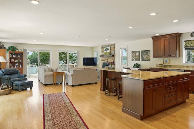 9 Blake Rd, Salem, NH 03079 - kitchen featuring open floor plan, light wood-style flooring, a kitchen island, recessed lighting, and light stone counters