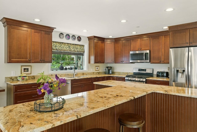 9 Blake Rd, Salem, NH 03079 - kitchen with appliances with stainless steel finishes, recessed lighting, a breakfast bar area, and light stone counters