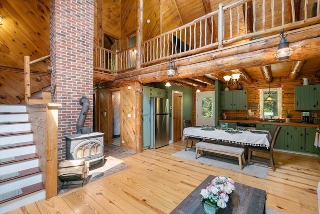 59 Ossipee Mountain Rd, Ossipee, NH 03814 - dining room with light wood finished floors, a towering ceiling, a wood stove, stairway, and wooden walls