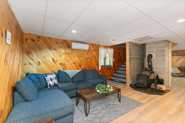59 Ossipee Mountain Rd, Ossipee, NH 03814 - living area featuring wooden walls, wood finished floors, an AC wall unit, a wood stove, and a paneled ceiling