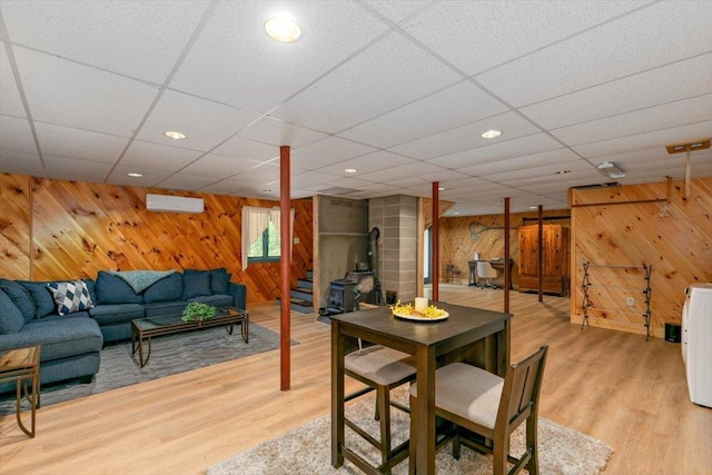 59 Ossipee Mountain Rd, Ossipee, NH 03814 - dining area with wooden walls, light wood finished floors, an AC wall unit, a paneled ceiling, and a wood stove