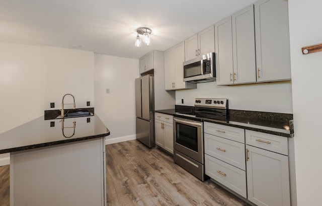 120 Fisherville Rd Unit 8, Concord, NH 03303 - kitchen featuring stainless steel appliances, wood finished floors, dark stone countertops, and a peninsula