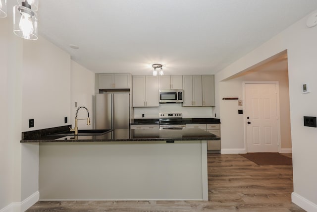 120 Fisherville Rd Unit 8, Concord, NH 03303 - kitchen featuring stainless steel appliances, a peninsula, wood finished floors, dark stone counters, and gray cabinetry