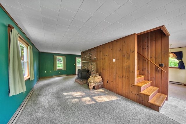 14 W Court Rd, Sunapee, NH 03782 - unfurnished room featuring a wood stove, stairs, carpet flooring, a baseboard heating unit, and wooden walls