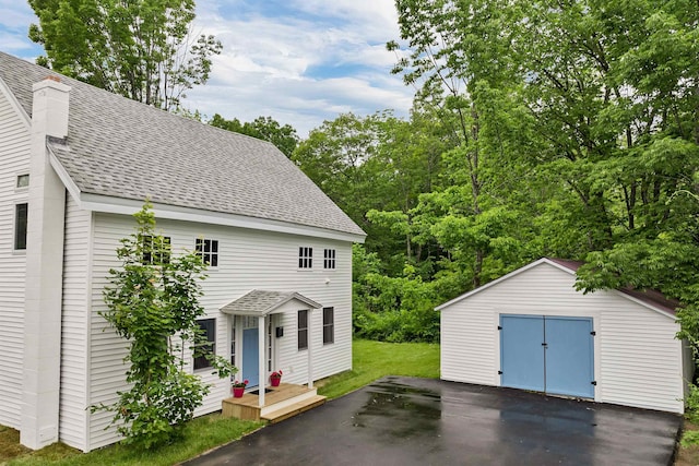 57 Central St, Farmington, NH 03835 - view of front of property with a shingled roof, a garage, an outbuilding, asphalt driveway, and a chimney