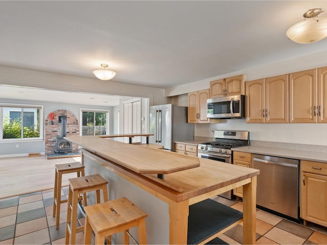 159 Loomis St, Burlington, VT 05401 - kitchen featuring stainless steel appliances, light brown cabinets, a wood stove, and light countertops