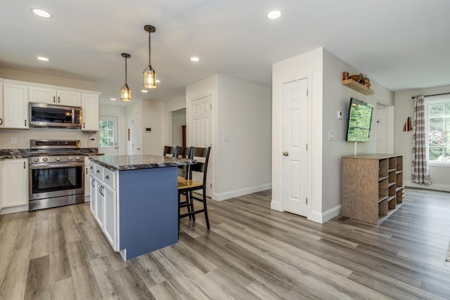 5 Turnpike St, Pembroke, NH 03275 - kitchen with appliances with stainless steel finishes, a breakfast bar, a kitchen island, white cabinets, and light wood-style floors