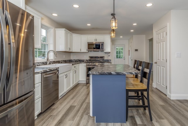 5 Turnpike St, Pembroke, NH 03275 - kitchen with stainless steel appliances, a center island, a breakfast bar, light wood-style floors, and white cabinets