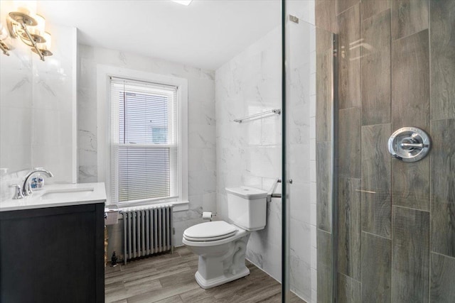 226 N St, Bennington, VT 05201 - bathroom featuring radiator heating unit, tile walls, vanity, a shower stall, and wood finished floors