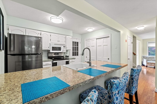 13 Judith Dr, Concord, NH 03301 - kitchen with appliances with stainless steel finishes, a breakfast bar, white cabinetry, and wood finished floors