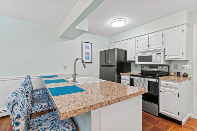 13 Judith Dr, Concord, NH 03301 - kitchen with stainless steel appliances, a peninsula, white cabinets, light countertops, and a breakfast bar area