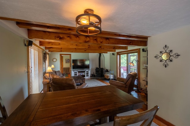 14 Mountain Ridge Rd, Ossipee, NH 03814 - dining room with beam ceiling, a wood stove, and a textured ceiling