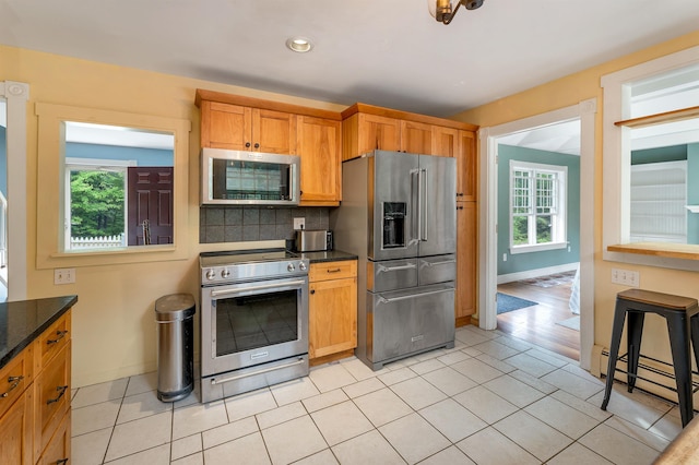 400 Turkey St, Tamworth, NH 03886 - kitchen with stainless steel appliances, a baseboard radiator, decorative backsplash, dark stone countertops, and light tile patterned flooring