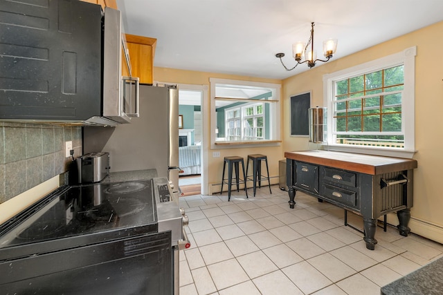 400 Turkey St, Tamworth, NH 03886 - kitchen featuring baseboard heating, a chandelier, light tile patterned flooring, range, and decorative backsplash