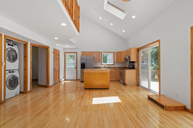 12 Cornwall Pl, Farmington, NH 03835 - kitchen featuring stainless steel appliances, stacked washing machine and dryer, a center island, light wood-type flooring, and high vaulted ceiling