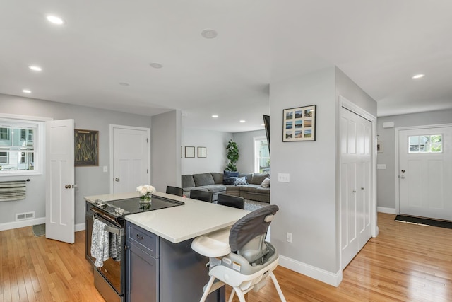 34 Leonard St, Rochester, NH 03867 - kitchen featuring electric stove, light wood finished floors, light countertops, a kitchen bar, and a kitchen island