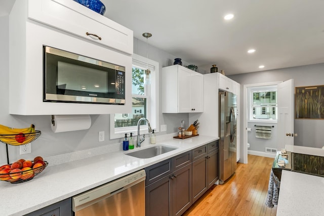 34 Leonard St, Rochester, NH 03867 - kitchen featuring appliances with stainless steel finishes, white cabinetry, recessed lighting, pendant lighting, and light wood-style floors