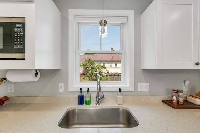 34 Leonard St, Rochester, NH 03867 - kitchen featuring stainless steel microwave, white cabinetry, hanging light fixtures, and light stone counters