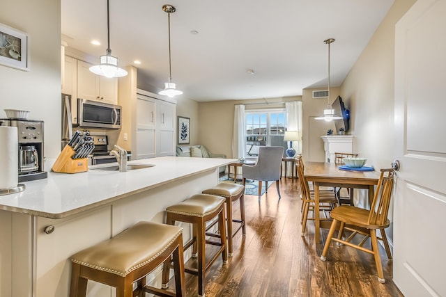 1 Ocean Ave Unit 210/212Fraction 3, York, ME 03909 - kitchen with stainless steel microwave, dark wood finished floors, a kitchen breakfast bar, white cabinetry, and decorative light fixtures