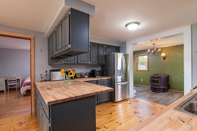 817 York Street Ext, Poultney, VT 05764 - kitchen with butcher block countertops, stainless steel appliances, light wood-style flooring, a chandelier, and a wood stove