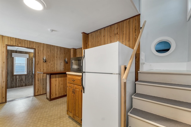 6 Davis Dr, Lebanon, NH 03766 - kitchen with freestanding refrigerator, black microwave, light flooring, brown cabinetry, and wood walls