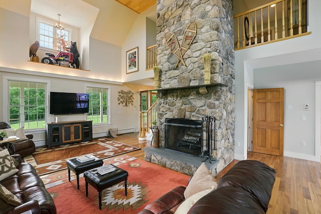 84 Shaw Rd, Northfield, NH 03276 - living area with high vaulted ceiling, wood finished floors, a stone fireplace, a chandelier, and a baseboard heating unit