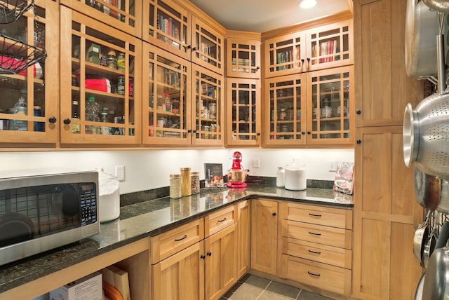 84 Shaw Rd, Northfield, NH 03276 - kitchen with stainless steel microwave, glass insert cabinets, dark stone counters, and light tile patterned floors