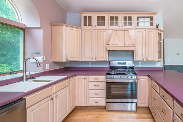 98 Rowell Rd, Lancaster, NH 03584 - kitchen with appliances with stainless steel finishes, custom exhaust hood, light brown cabinets, light wood-style floors, and glass insert cabinets