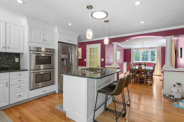 397 Strafford Rd, Strafford, NH 03844 - kitchen featuring decorative columns, stainless steel appliances, white cabinets, a breakfast bar area, and crown molding