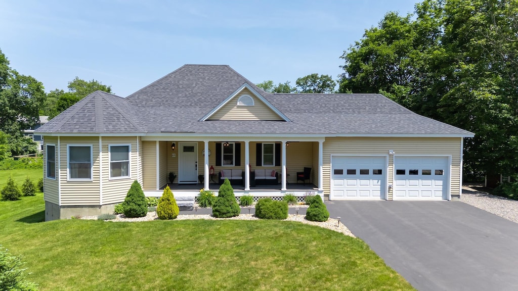 69 Knight St, Milford, NH 03055 - view of front of house featuring a porch, a garage, roof with shingles, asphalt driveway, and a front lawn