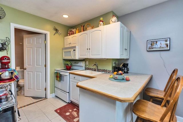 76 Cunningham Pond Rd, Peterborough, NH 03458 - kitchen featuring white appliances, a kitchen breakfast bar, tile counters, a peninsula, and light tile patterned floors