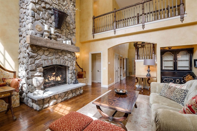 44 Buker Way, New London, NH 03257 - living area featuring a towering ceiling, arched walkways, hardwood / wood-style flooring, and a stone fireplace