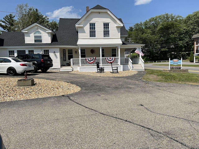 144 Lake St Unit 19, Laconia, NH 03246 - view of front of property with covered porch, a shingled roof, driveway, and a chimney