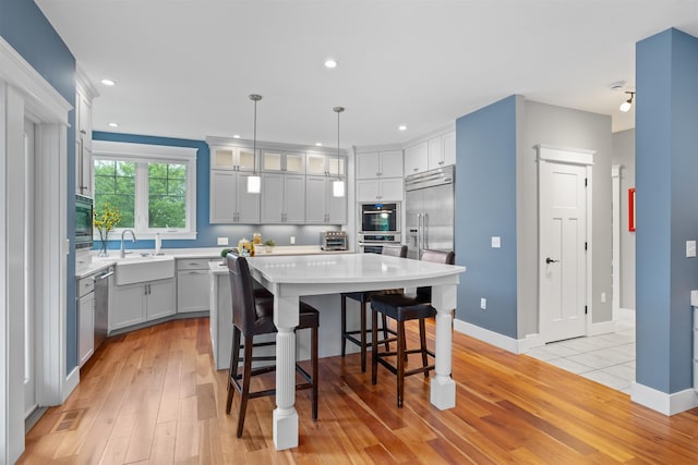 74 Childs Dr, Dover, NH 03820 - kitchen featuring appliances with stainless steel finishes, light wood finished floors, light countertops, a kitchen bar, and recessed lighting