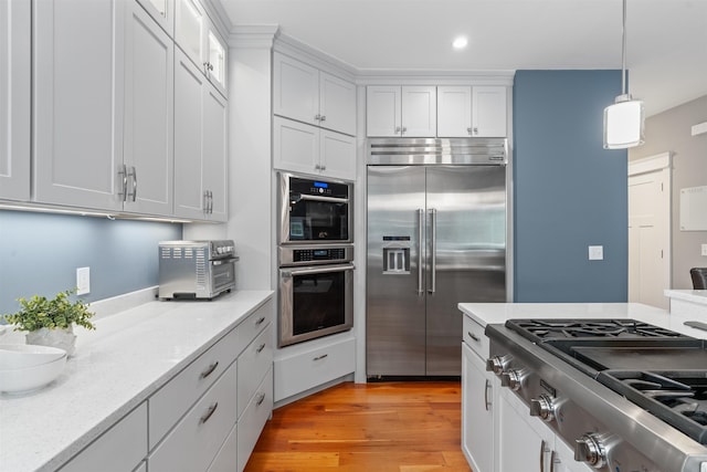 74 Childs Dr, Dover, NH 03820 - kitchen with appliances with stainless steel finishes, white cabinets, light wood-style floors, recessed lighting, and hanging light fixtures