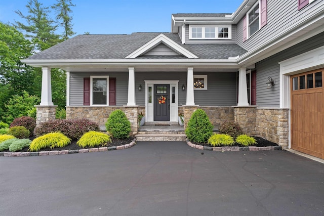 74 Childs Dr, Dover, NH 03820 - view of front of property featuring stone siding, a porch, roof with shingles, and a garage