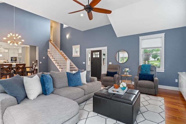 74 Childs Dr, Dover, NH 03820 - living area with high vaulted ceiling, stairway, ceiling fan, light wood finished floors, and a chandelier